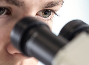scientist looking through microscope