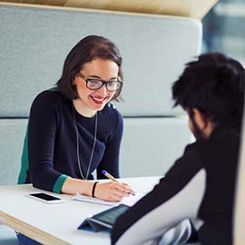 a group of people sitting at a table using a laptop