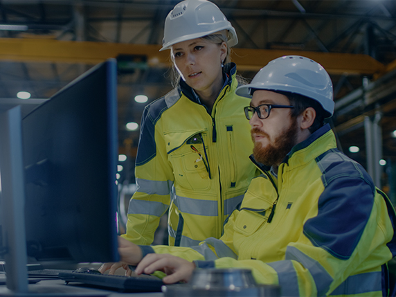 two people in hard hats on a computer