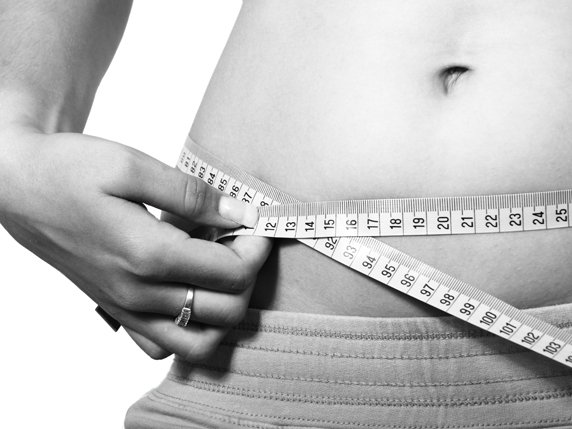 Person measuring waist with tape measure