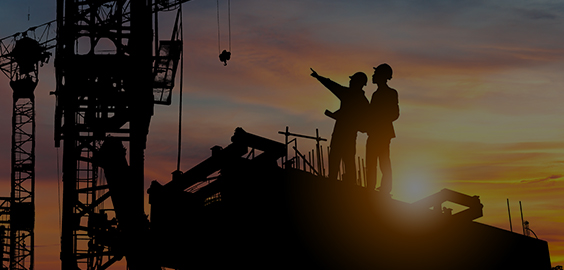 two workmen on a building site with cranes in the background