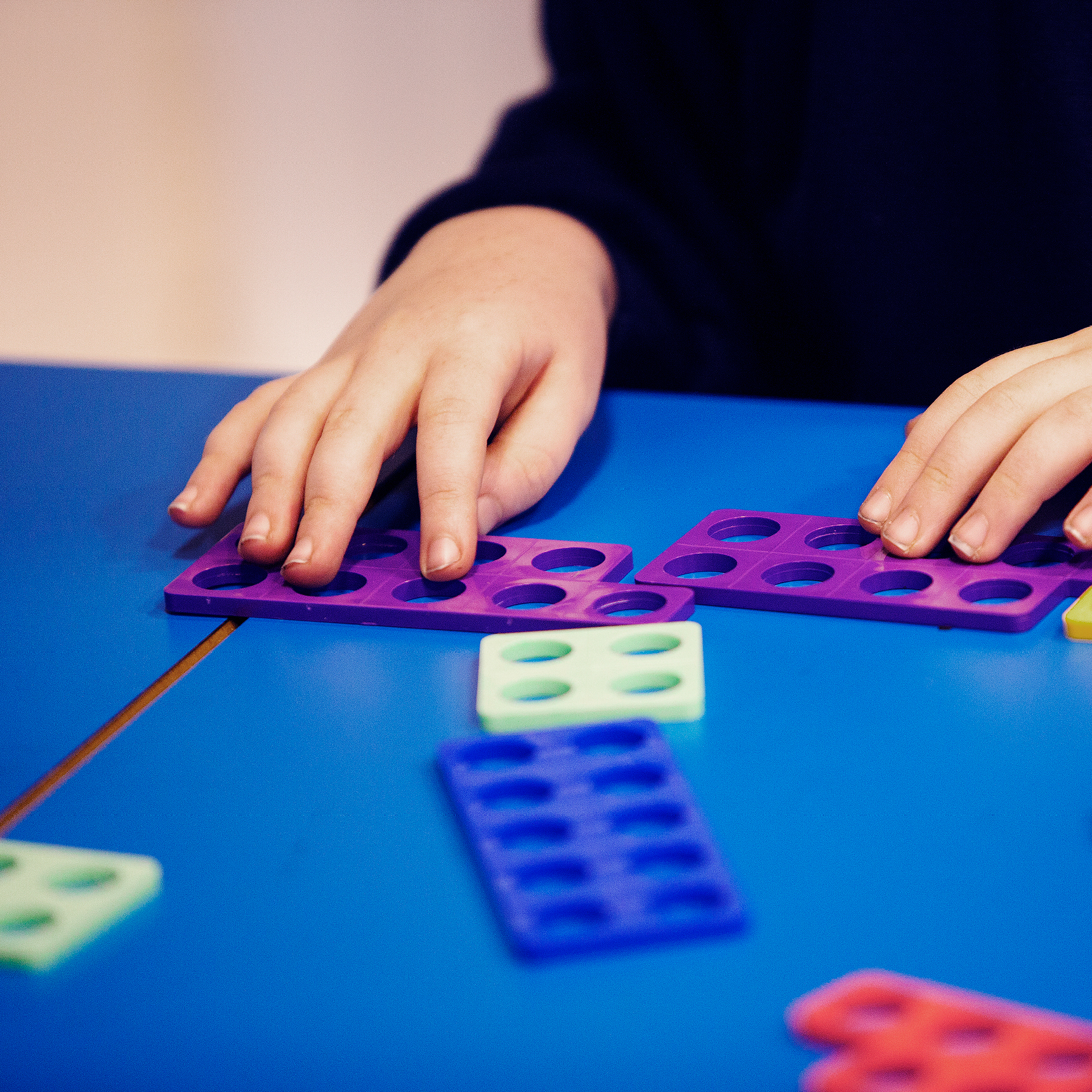 a childs hands arranging a colourful toy that teaches maths