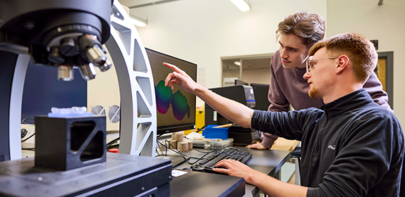 Two engineering students using specialist equipment.