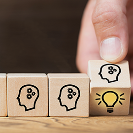hand turning wooden cubes with light bulb engraving