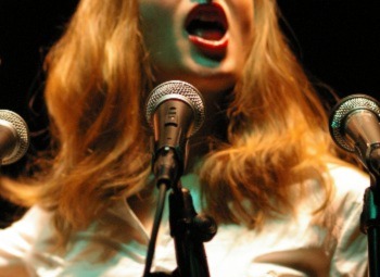 person singing into three microphones