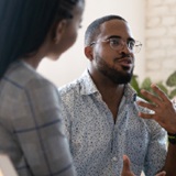 Excited black man sitting next to a black woman and talking