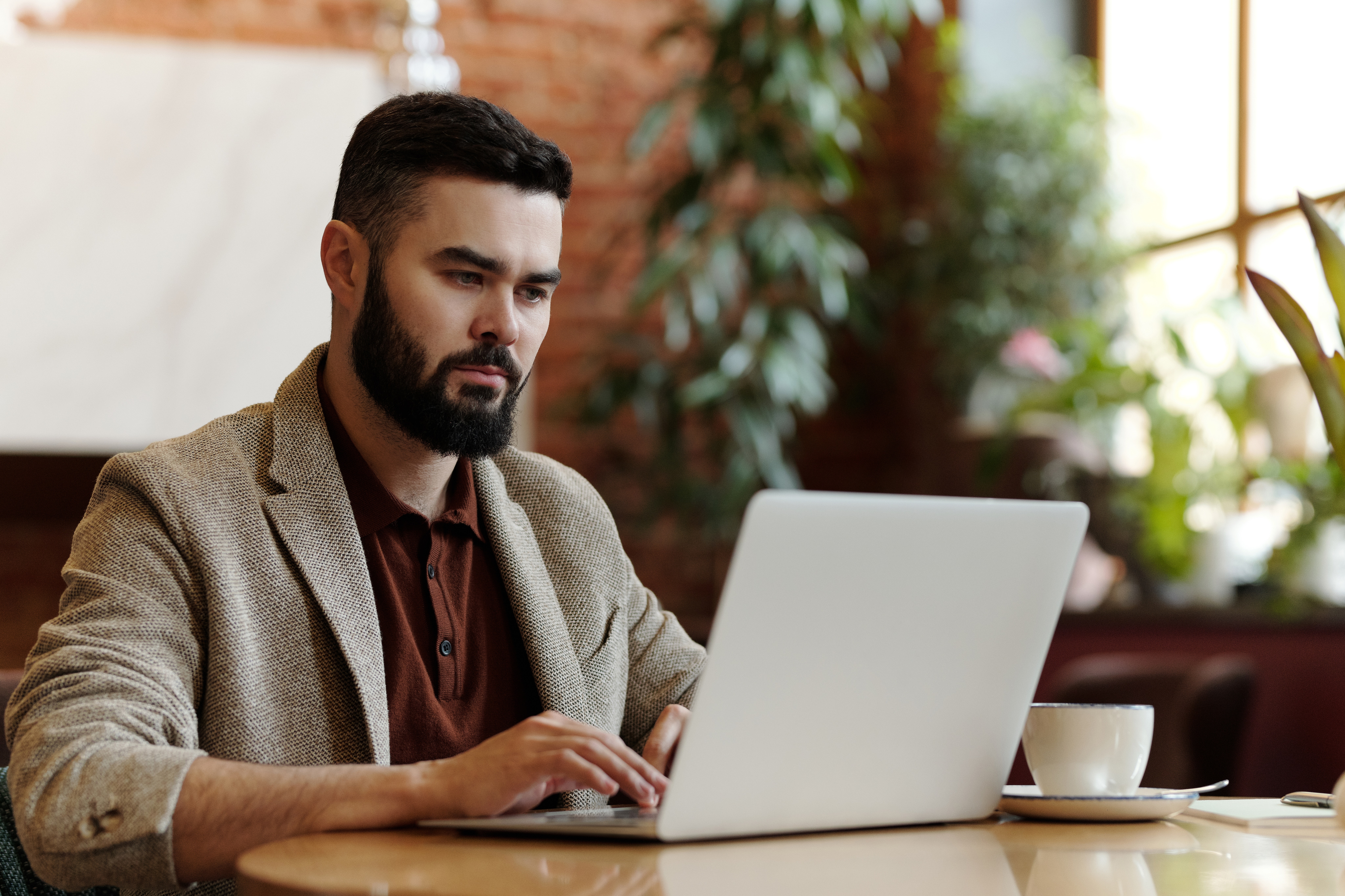 Photograph of a man sat at a desk with his laptop with an expression of focus