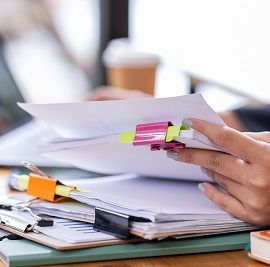 Person flicking through a series of reports laid on desk