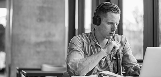 Man working at a laptop wearing headphones 