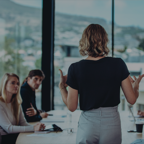Female worker addressing a room of colleagues.