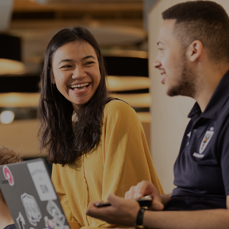 A male and female student sat in Student Central, laughing.