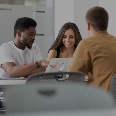 Three students gathered around a table, making notes together.