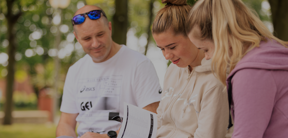 Father looking at a Northumbria prospectus with his two daughters.