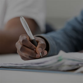 Image of a students hand with a pen in their handing writing notes.