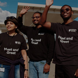 Female and male students waving to arriving international students at the Newcastle International Airport.