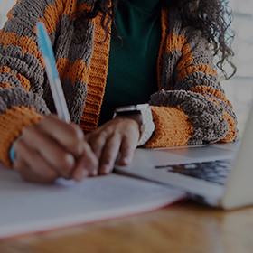 Close up of an individual making notes in an exercise book