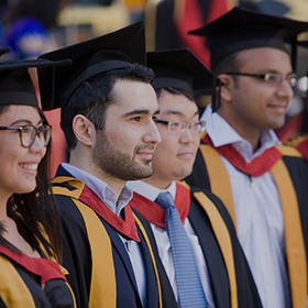 Four graduating students lined up in their robes