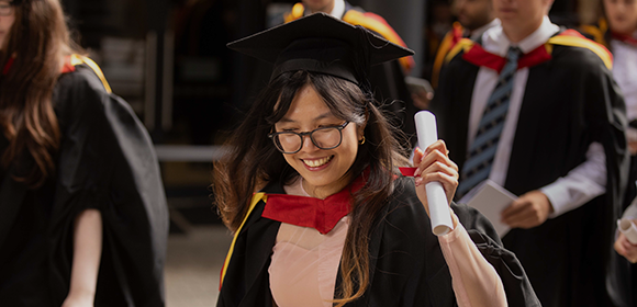 Malaysian Northumbria graduate holding their diploma after graduation.