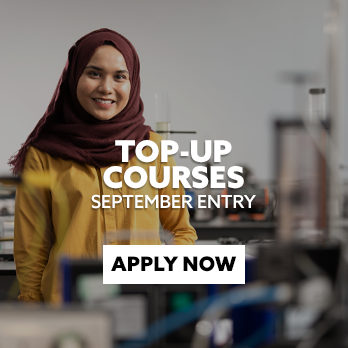 Female STEM student stood in a lab, looking directly at the camera and smiling. Text embedded on the image reads: "Top-Up Courses - Apply Now"