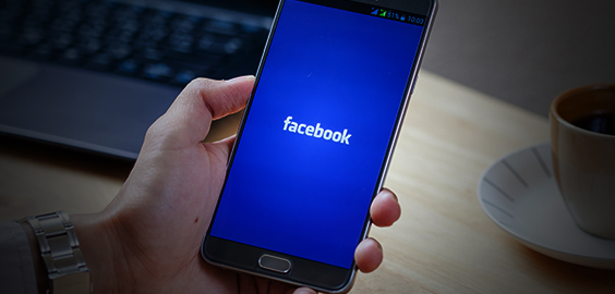 a hand holding up a laptop computer sitting on top of a table