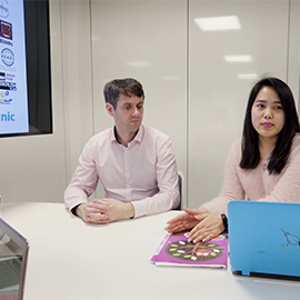 a group of people sitting at a table using a laptop computer