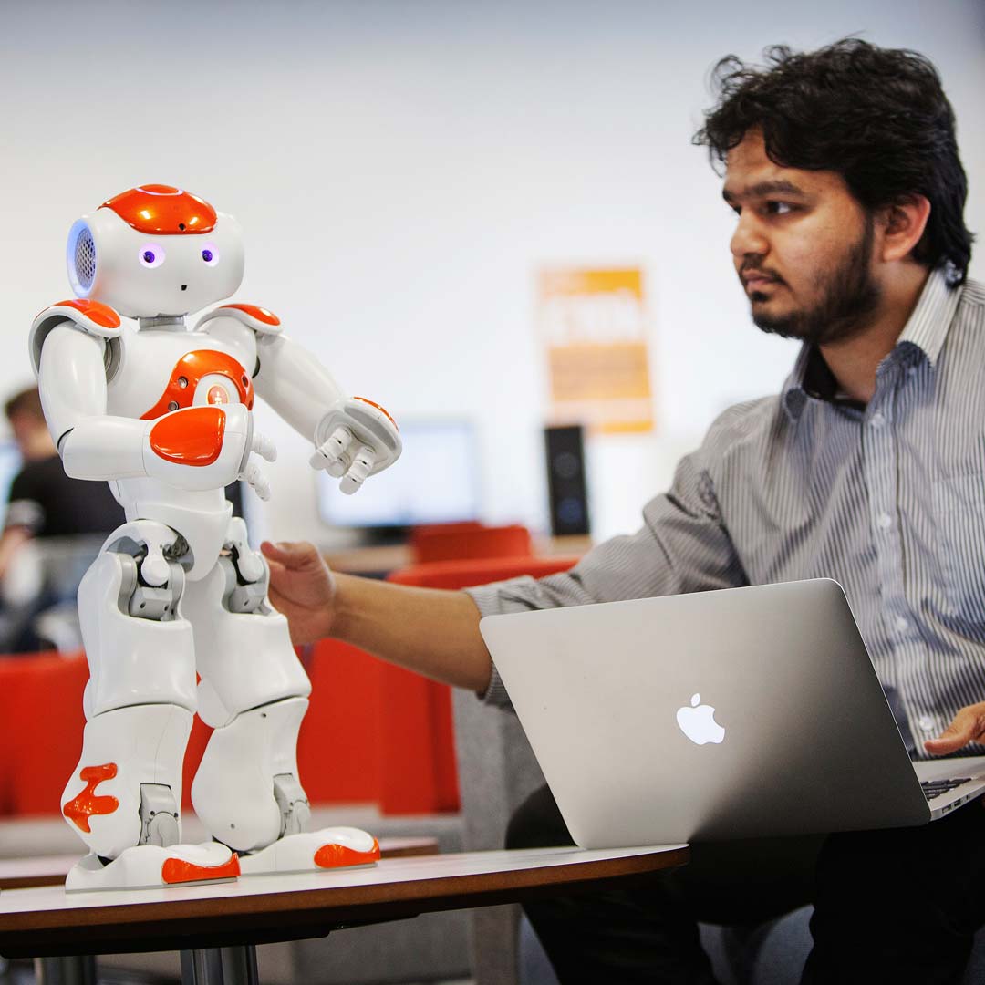 a man using a laptop computer sitting on top of a table