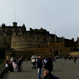 a group of people walking down a street next to tall buildings