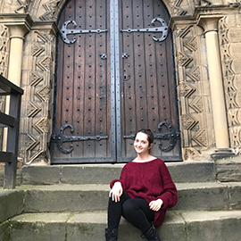 a person sitting on a bench in front of a stone building