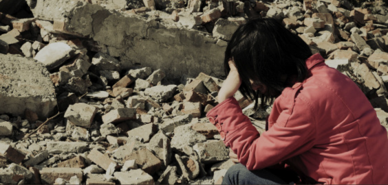 person crouched in front of rubble