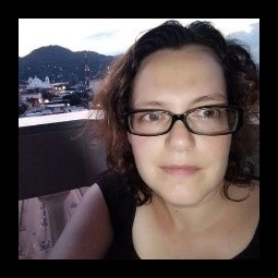 a woman wearing glasses and smiling at the camera