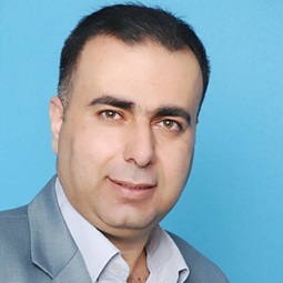 a man wearing a suit and tie smiling and looking at the camera