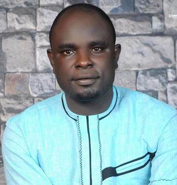 a man standing in front of a brick wall