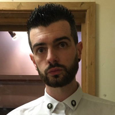 a man wearing a suit and tie smiling at the camera