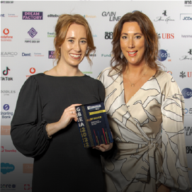 two women smiling with an award