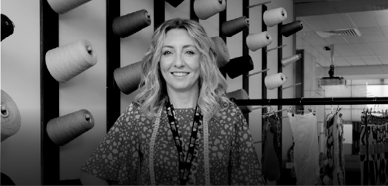 woman smiling to camera in front or reels of ribbon