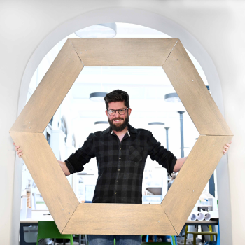 Caption:Dr Henrik Melin pictured with a life-sized replica of one of the Webb telescope’s 18 individual hexagonal mirrored panels.
