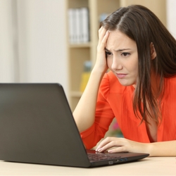 a woman sitting at a table using a laptop computer
