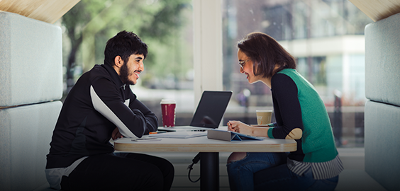 Two people sitting across from each other at a table smiling