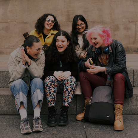 Image: 5 students sat, laughing at the bottom of Grey's Monument.