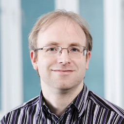 a man wearing glasses and smiling at the camera