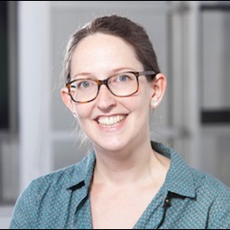 a woman wearing glasses and smiling at the camera