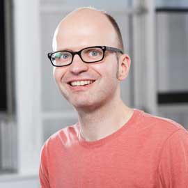 a person wearing glasses and smiling at the camera