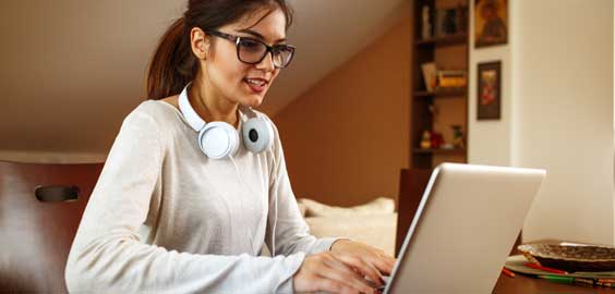 a person wearing glasses sitting at a table using a laptop