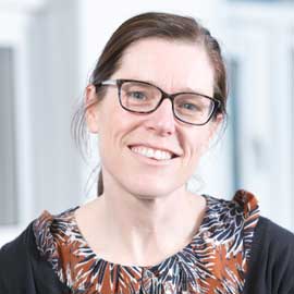 a woman wearing glasses and smiling at the camera