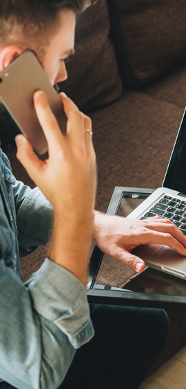 a man using a laptop computer talking on a cell phone