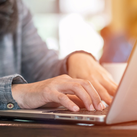 a person using a laptop computer sitting on top of a table