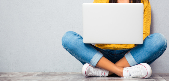 A person sitting crossed legged with a laptop on their lap