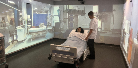 man stood over medical training dummy on hospital bed