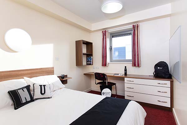 a bedroom with a bed and desk in a room