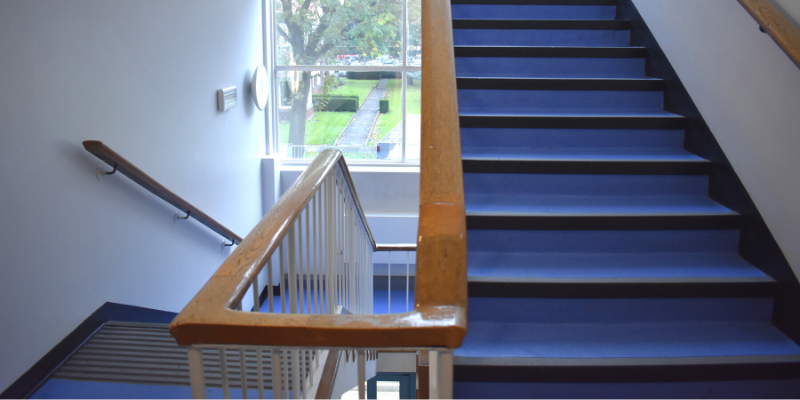 Blue staircase with light wood banister.
